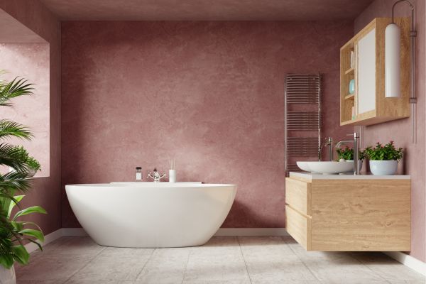 Salle de bain élégante avec baignoire blanche, mur rose et meuble-lavabo en bois