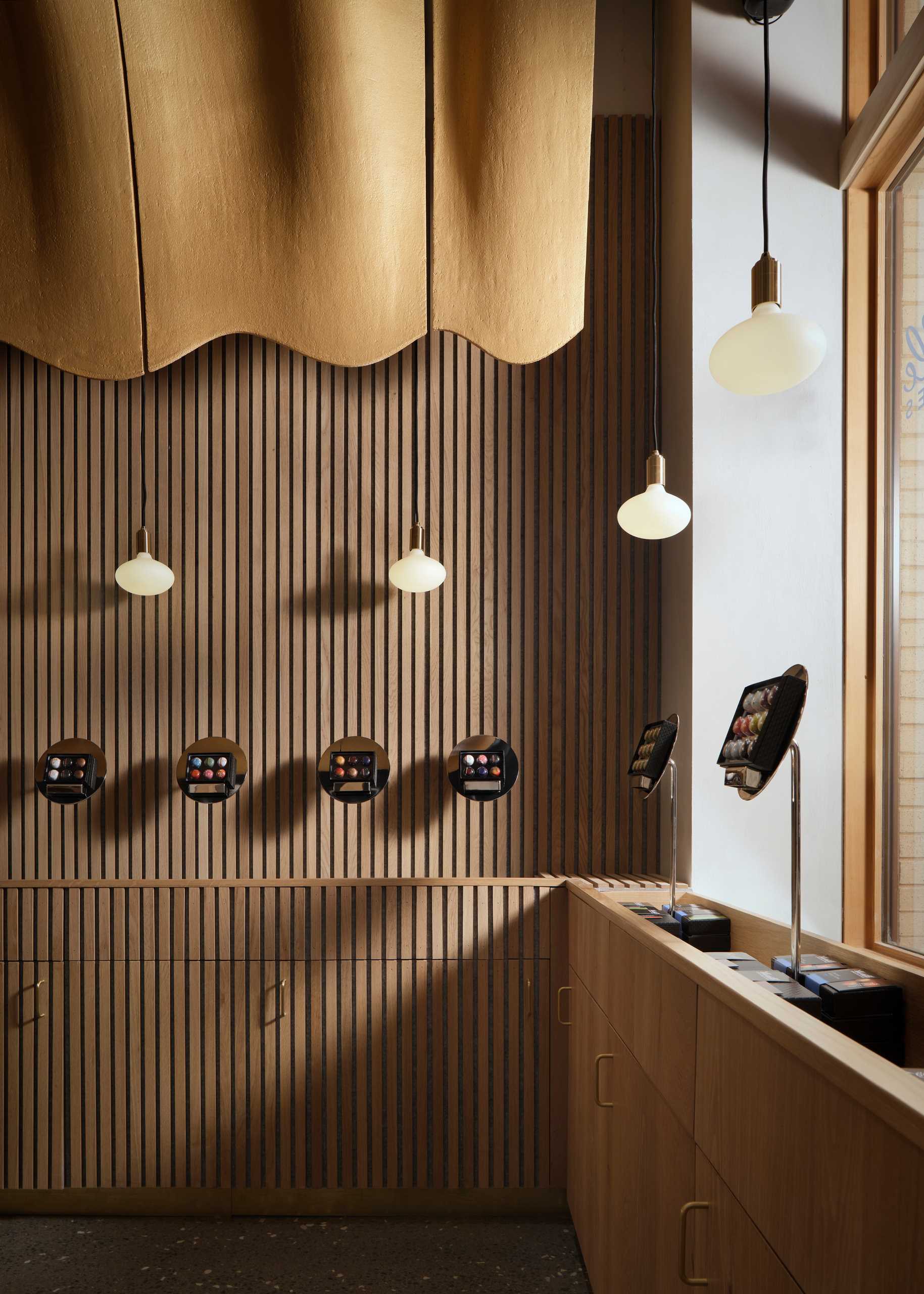 Détail du design intérieur avec lampes suspendues et présentoirs en bois dans une boutique de chocolat de luxe