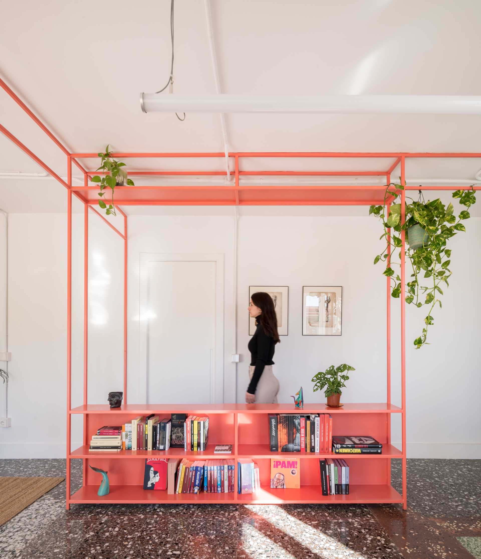 Bibliothèque colorée avec plantes suspendues intégrées dans un appartement contemporain.