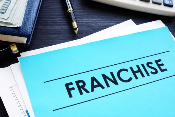 Dossier de franchise sur un bureau avec stylo et calculatrice, symbolisant l'investissement et le choix d'une franchise.