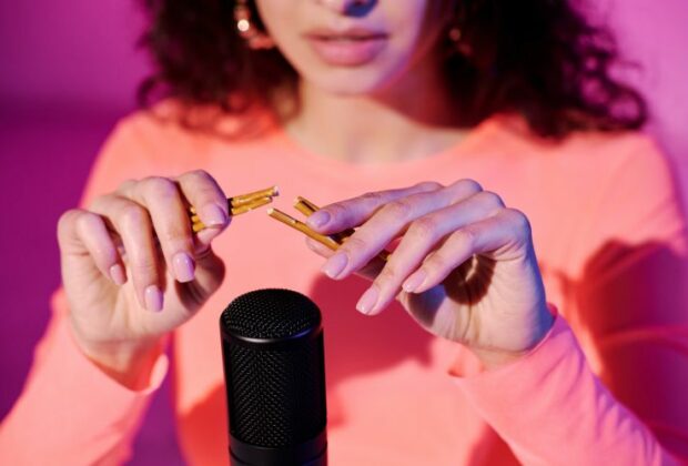 Femme pratiquant l'ASMR avec des bâtons en bois devant un microphone pour créer des sons relaxants.