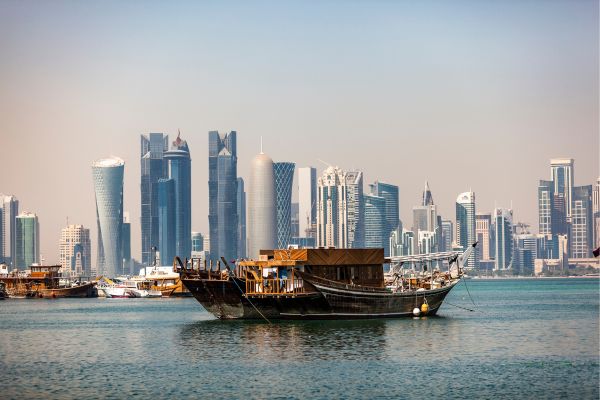 Bateaux traditionnels Dhow naviguant dans la baie de Doha avec les gratte-ciels en arrière-plan.