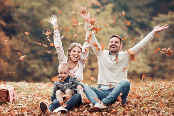 Famille heureuse jouant dans les feuilles d'automne, profitant d'un moment de déconnexion en plein air.