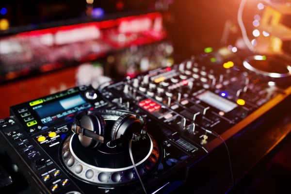 Vue rapprochée de l'équipement DJ professionnel, incluant des platines, un contrôleur et des casques, utilisés pour mixer de la musique dans une ambiance live.