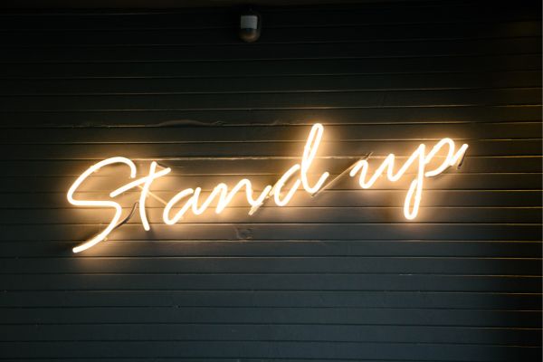 Enseigne lumineuse "Stand up" illustrant l'essor des humoristes sur les réseaux sociaux.