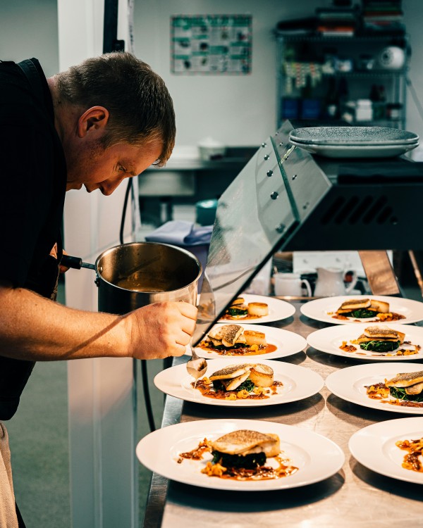 Chef cuisinier dressant des plats en cuisine, symbolisant l’efficacité et l’innovation dans la restauration grâce aux outils d’intelligence artificielle.